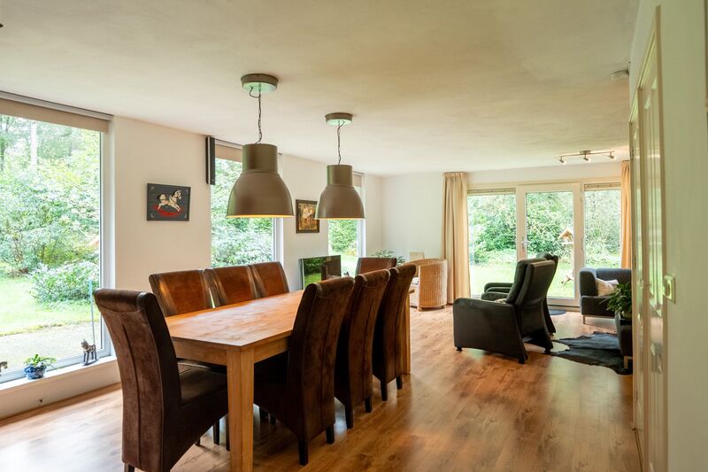 Woonkamer met eettafel en grote tuinramen